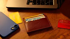 Mobil, peněženka s kartami a notebook na dřevěném stole v kanceláři.