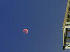 Krvavý měsíc na noční obloze vedle kovové konstrukce, zatmění Měsíce, astronomie
