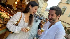 Mladý pár se směje a drží pivo na tržišti v centru města.