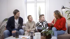 Rodina čtyř lidí v obýváku u černého ventilátoru na stole