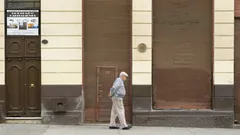 Muž v šedém svetru chodí ráno po ulici