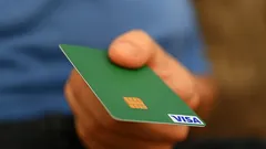 Ruka držící zelenou platební kartu Visa s čipem